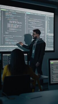 Vertical Screen: Teacher Giving Computer Science Lecture to Diverse Multiethnic Group of Students in Dark College Room. Projecting Slideshow with Programming Code. Explaining Information Technology.