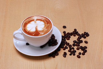 Hot latte coffee cup and beans isolated on wooden table