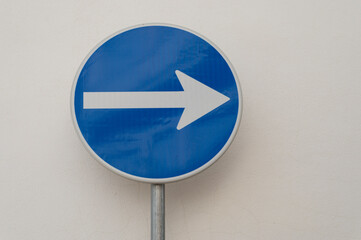 blue right turn traffic sign against a white wall.
