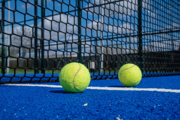 three balls near the net in a blue paddle tennis court