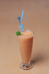 Glass of Sapodilla smoothie or milkshake with fresh fruit classically decorated on wooden table for...