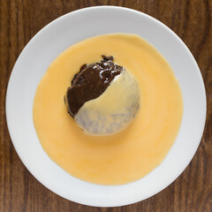 Top view of chocolate sponge pudding with custard on a wooden table surface