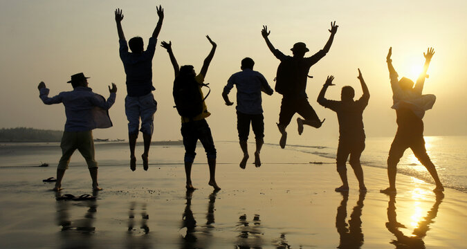 Big group of seven happy friends is having fun and jumping on beach during sunset time at Kuakata sea beach, Bangladesh