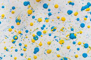 Blue and yellow paint drops on white canvas.
