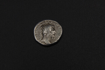 Silver ancient Roman coin on a black background