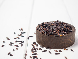 pile of black rice in a wooden bowl on a wooden table close-up
