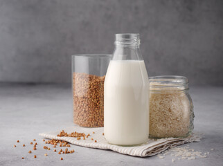 Non dairy alternative milk. Vegan buckwheat and rice milk close up. The concept of healthy vegetarian food and drinks. Copy space. A bottle of raw milk on a gray table and napkin. Diet healthy concept