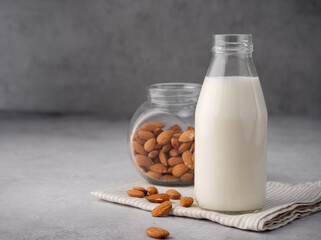 Almond organic vegan milk with almonds in glass on a gray concrete background. Copy space. Close up. Non dairy alternative milk. The concept of healthy vegetarian food and drinks. Diet healthy concept