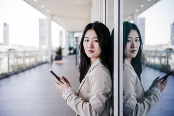 Obraz premium confident beautiful chinese business woman using mobile phone in city. Technology
