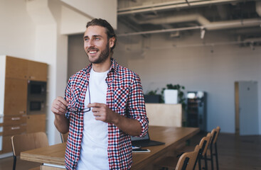 Cheerful Caucaisan male 20 years old looking away and smiling in coworking space, smart casual...