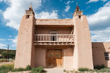 Historic adobe church with wood beams and door topped by rustic crosses in Las Trampas, New Mexico...
