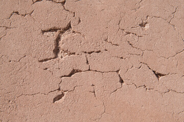 Background image showing a heavily textured and cracked rustic plaster adobe wall with flecks of straw - traditional building materials in an old church in New Mexico