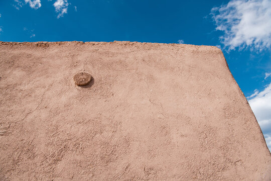Close-up view of the corner of a rustic, textured and cracked adobe wall with flecks of straw - Las Trampas, New Mexico