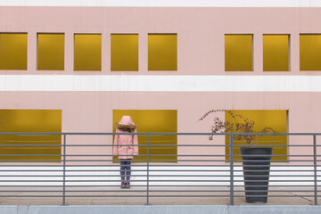 petite fille triste en rose devant une façade colorée