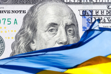 ukrainian national flag on foreground and US one hundred dollars paper currency on background....