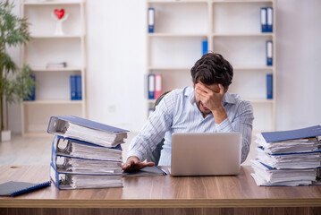 Young male employee unhappy with excessive work in the office