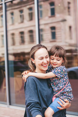 Young woman carrying her little daughter