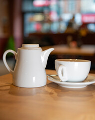 White tea pot and tea cup in a saucer