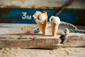 Closeup of two ice cream cones covered with caramel syrup on a wooden desk