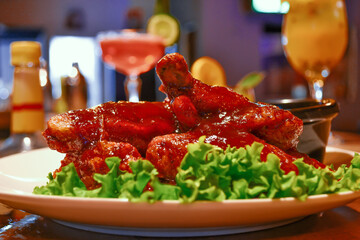 View of chicken wings fried, with lettuce and dip. Snack with bar in background.
