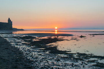 Sunset over the beach next to the Castle. Colour sky painted tide out bare sand and reflection into the water.