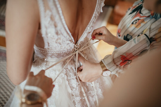 Bridesmaids helping gorgeous bride to dress up and get ready for her wedding ceremony. 