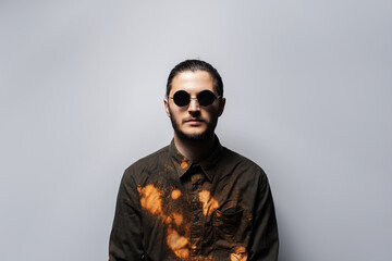 Portrait of young confident man wearing round sunglasses on grey background.