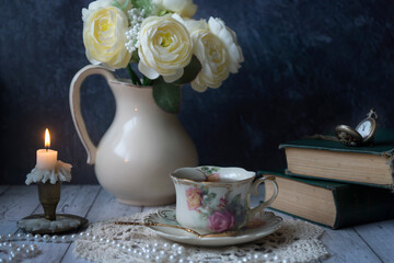 Vintage still life, a cup of tea, a clock, old books and other old things.