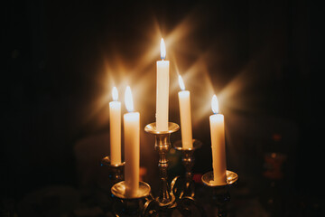 Burning candles on an old brass candlestick against a black background