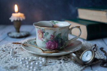 Vintage still life, a cup of tea, a clock, old books and other old things.