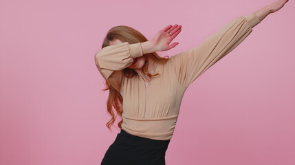 Trendy positive businesswoman girl in blouse having fun dancing and moving to rhythm, dabbing raising hands, making dubdance gesture. Young woman on pink studio background. People sincere emotions