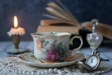 Vintage still life, a cup of tea, a clock, old books and other old things.