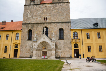 Fototapeta na wymiar Tepla, Czech Republic, 7 August 2021: Premonstratensian Abbey and monastery, Romanesque church of the Annunciation with towers, gothic arched portal with stone carved statues of saints at summer day