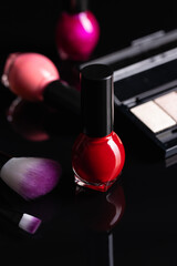 Set of cosmetic makeup products. Eyeshadow, nail polish and makeup brushes on black table.