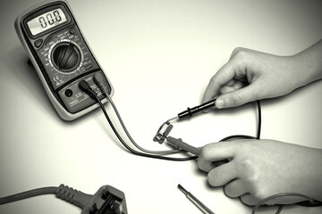 Multimeter cable probes used to test a household fuse.