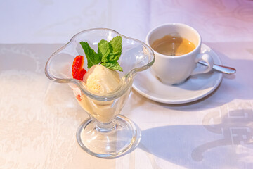 Vanilla ice cream with strawberries and mint is in a glass cup
