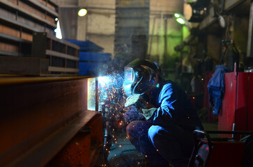 Workers wearing industrial uniforms and Welded Iron Mask at Steel welding plants, industrial safety first