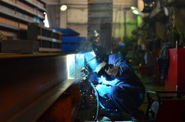 Workers wearing industrial uniforms and Welded Iron Mask at Steel welding plants, industrial safety...