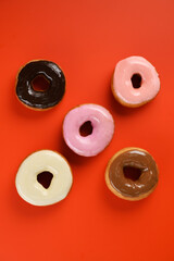 donuts covered with colored icing on a red background
