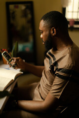 Portrait of a black gardener scrolling on his mobile phone at home