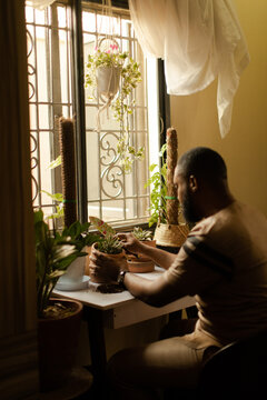 wide show of a black male doing self care at home with plants 
