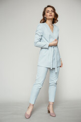 A model in a blue pantsuit on a studio background. Shooting fashion clothes