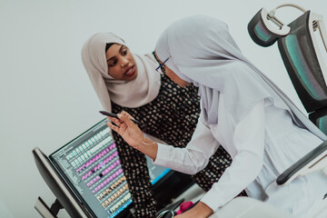 Friends at the office two young Afro American modern Muslim businesswomen wearing scarf in creative bright office workplace with a big screen