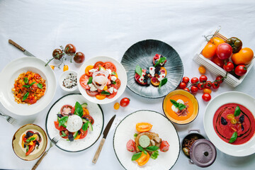 Variety of dishes on the table. Tomato menu in the restaurant, tomato soup, mix of tomatoes with buffalo mozzarella and pesto, pork fillet with baked tomatoes, pasta with tomato sauce, tomato salad. 