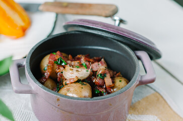 Fried potatoes with bacon in a roasting pot.
