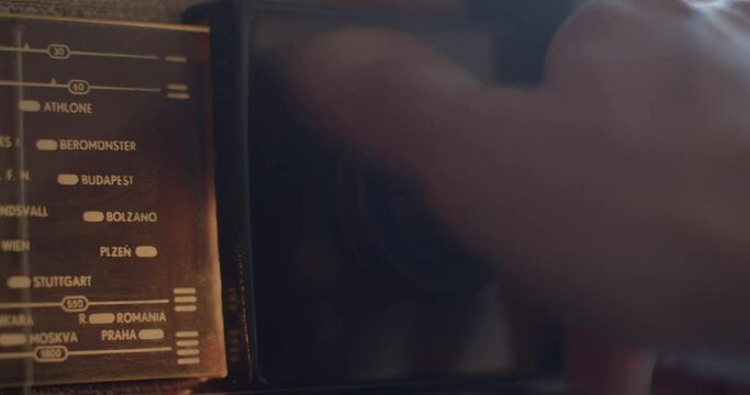 The hand turns the radio tuning knob in the evening. Looking for an interesting wave to listen to. Index of radio stations by cities.