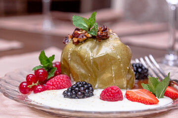 Baked apple with honey, nuts, berries and white sauce