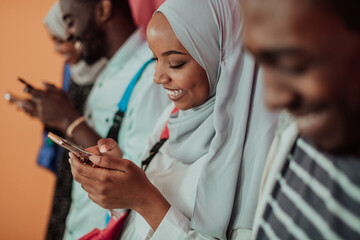 A group of African Muslim students use smartphones while standing in front of a yellow background