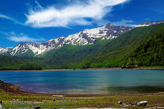 View over isolated crater lake on partly black snow capped Volcano Llaima contrasting with blue sky -  Conguillio NP in central Chile;