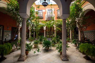 Fototapeta premium Andalusian style, patio with green plants and arches, old town Seville, Spain